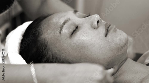 Young Asian woman receiving relaxing Thai facial massage in spa salon