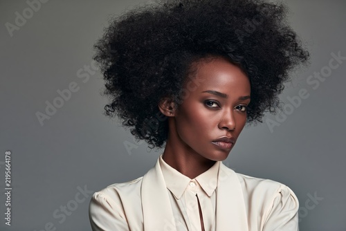 Portrait of a confident young woman with natural afro hairstyle against grey background