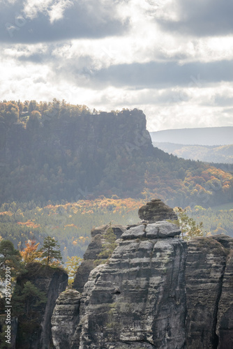 Nature and travel landscape in Saxon Switzerland, Germany, with dramatic sandstone cliffs, rugged rock formations, autumn woodland and distinctive tabletop mountain.