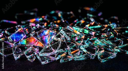 Shattered glass fragments catching iridescent light during a macro close-up with dramatic studio lighting