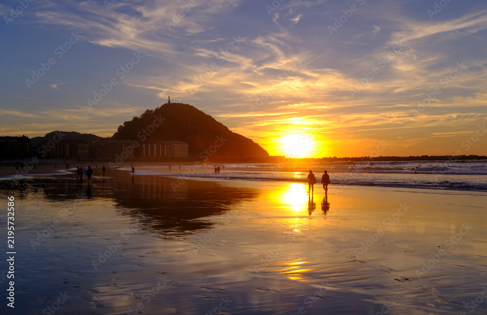 Obraz premium Golden Sunset Over Zurriola Beach and Ocean Waves in San Sebastian