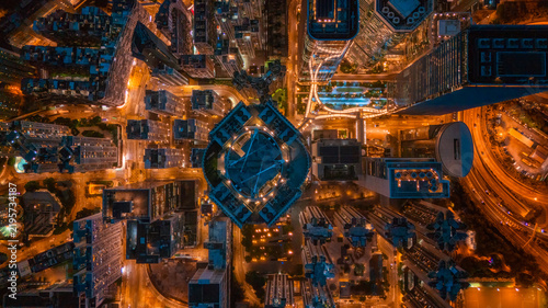 Top-down view of a circular plaza glowing blue amid orange city lights at night
