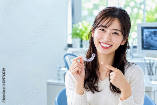 Plakat マウスピース矯正具を持って笑顔を見せる女性