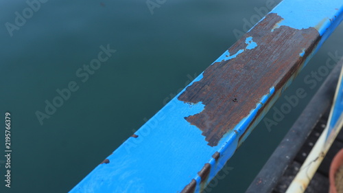 Close up view of peeling paint and rust corrosion on an old black iron fence surface needing maintenance