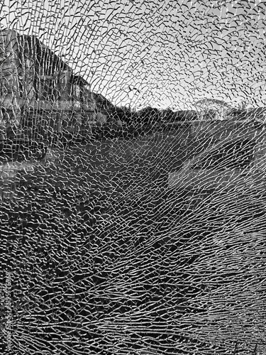 фотографія Black and white photograph showing fractured glass with an urban scene visible behind the cracked surface