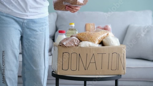 The woman received donation box with food. She takes the packaged cereals out of the box.