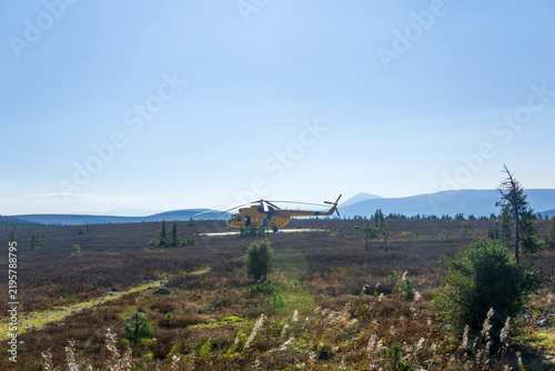 Helicopter in the field of tundra in the mountains.