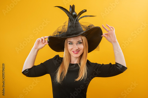 Obraz na płótnie Young woman smiling while adjusting a pointed hat with mesh details and feathers