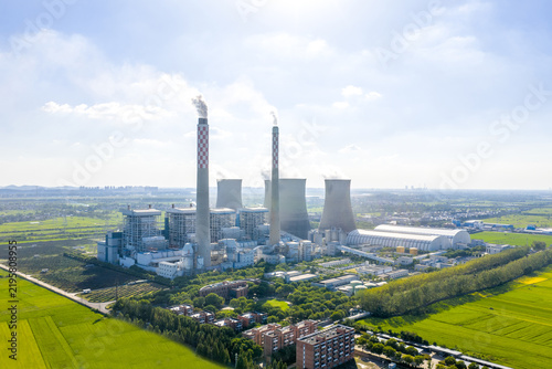 Modern thermal power plant under blue sky with cooling towers and green fields