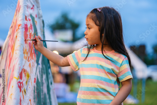preschool child girl painting watercolors on canvas outdoors in park