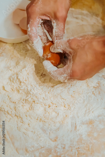 Foto Hands breaking egg into flour for pasta dough close up