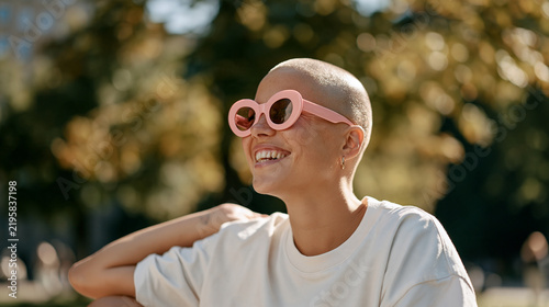 A man with a shaved head wears novelty sunglasses and a confident grin in a sunny autumn park on be bald and be free day, celebrating self acceptance, body confidence,