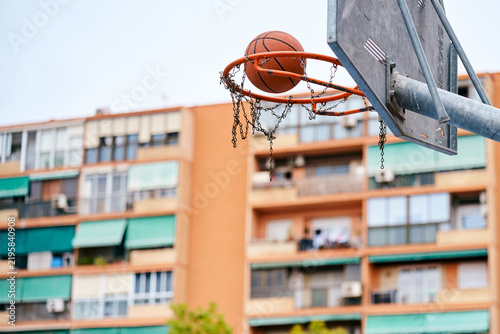 Basketball passing through hoop net in urban setting