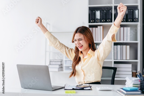 Принти на полотні Asian Adult Woman Celebrating Success at Work With Arms Raised in Joyful Exubera