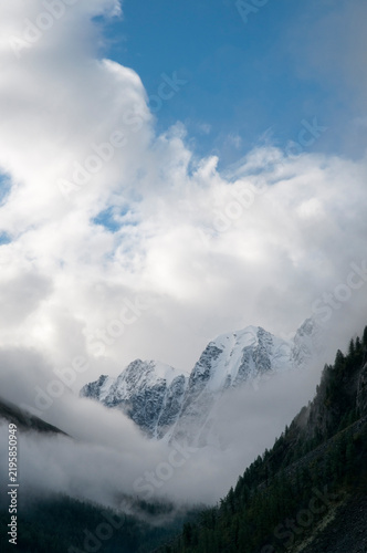 Morning view of mountain peaks named Dream, Fairy Tale and Beauty covered with thick white clouds, Russia, the Altai Republic