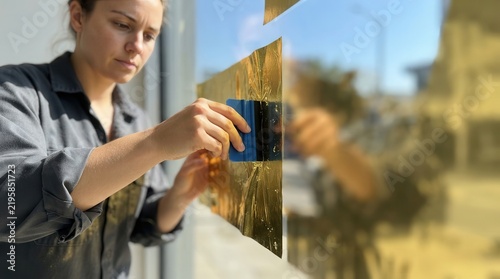 Technician Applying Reflective Gold Solar Film to Window