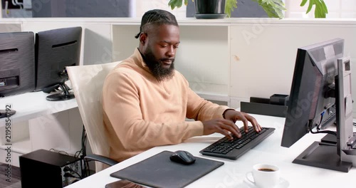 Business professional working on computer at office desk with coffee nearby
