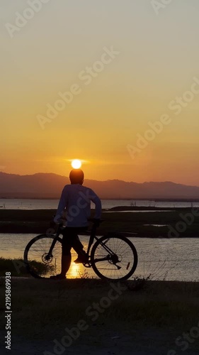 Silhouette of Cyclist at Sunset by Lake