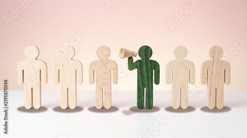 Leadership concept with green wooden figure holding megaphone among neutral figures on white surface