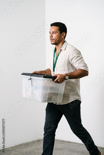 Adult Male Employee Carrying a Transparent Plastic Storage Box While Moving to a New Office