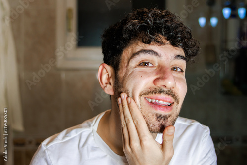 Фотография Young man smiling and touching his face exploring his fresh and clean skin