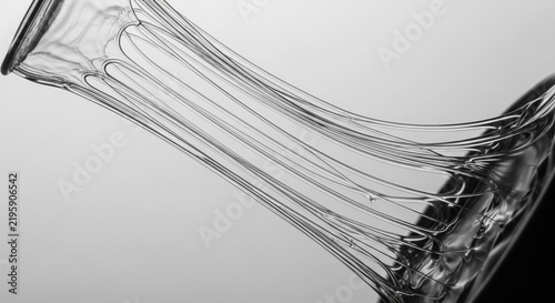 Close-up macro of thin, stretching liquid strands forming a delicate abstract texture