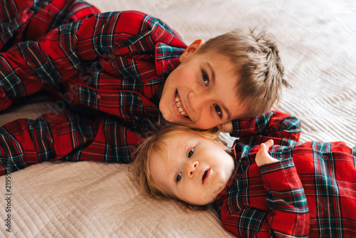 Obraz na płótnie Two brothers lying together on a bed in matching red plaid shirts