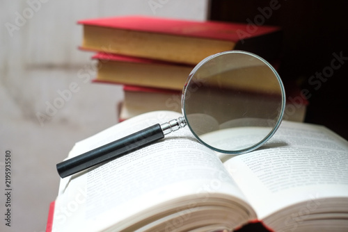 Magnifying glass rests on open book, concept of learning and discovery process.