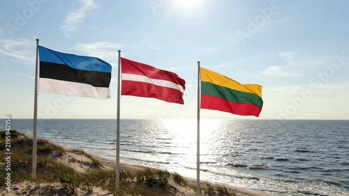 Baltic states flags waving together: estonia, latvia, and lithuania national flags on a sunny coastal beach background