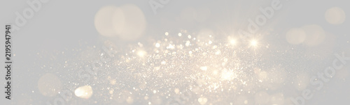 Fotografie A dynamic spread of golden glitter particles sparkles against a black background