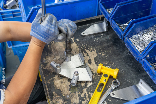 Workers assembling metal hardware fittings wearing gloves