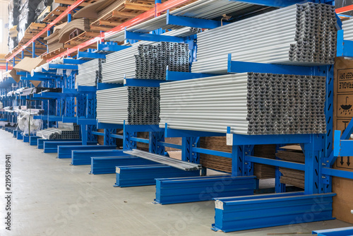 Mass raw aluminum profiles neatly stored on blue warehouse shelves