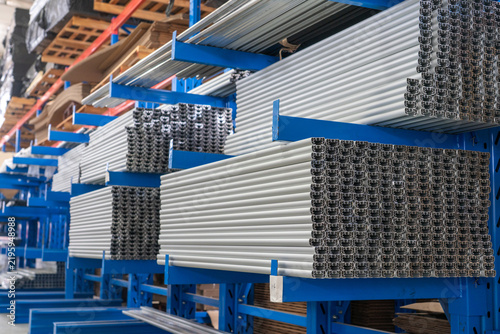 Raw aluminum industrial profiles neatly stacked on warehouse storage shelves
