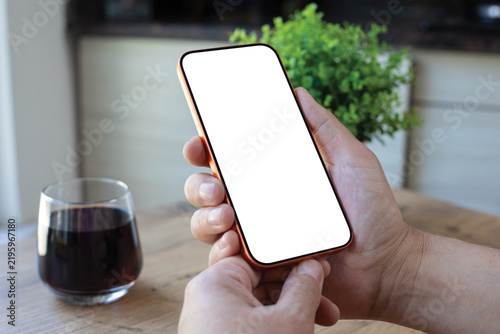 Man hand holding phone blank white screen mockup office desk