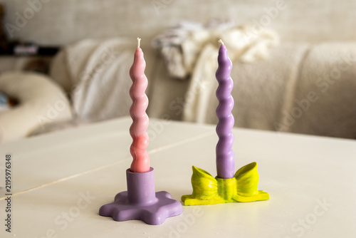 Fotografie Purple and pink spiral taper candles displayed in colorful sculptural candle holders on a table in a cozy home interior