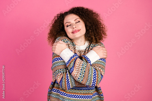 Canvastavla Young woman hugging herself in a colorful knitted sweater, cozy and relaxed, exp