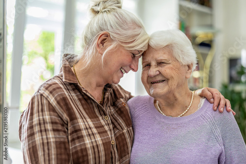Happy senior woman and her adult daughter at home
