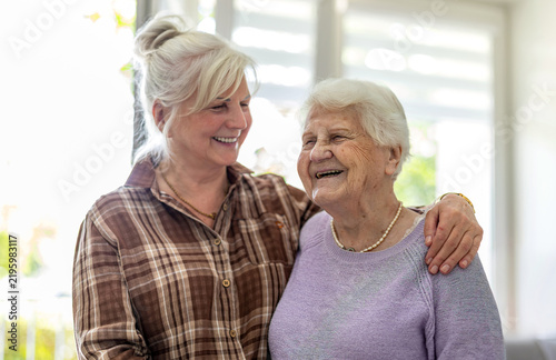 Happy senior woman and her adult daughter at home
