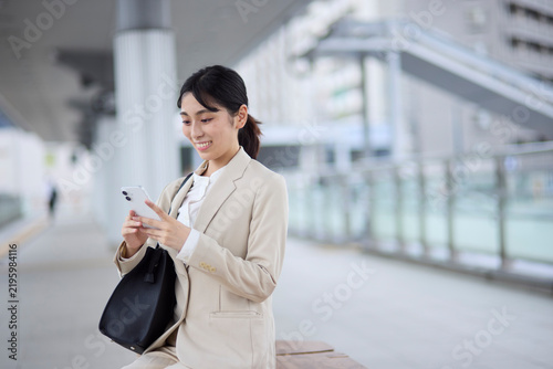 Obraz w ramie 駅の連絡通路でスマートフォンを操作するビジネスウーマン
