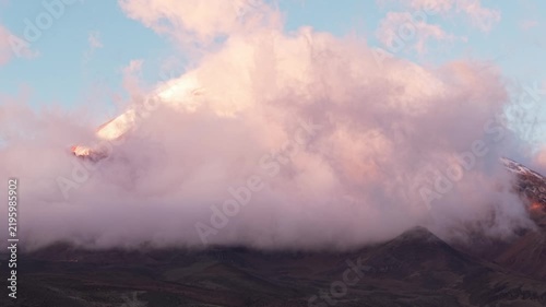 Pink clouds moving in slow motion around the snowy summit of chimborazo volcano in ecuador