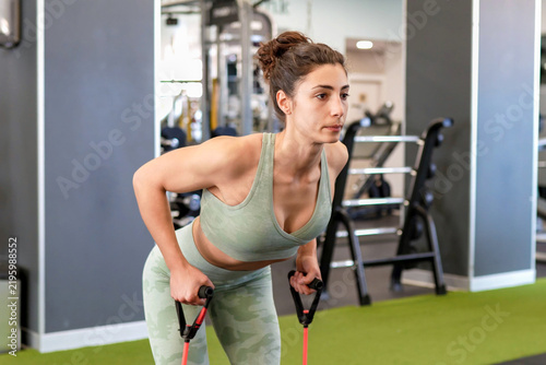 Woman concentrates fully on resistance band rowing exercise guided professionally