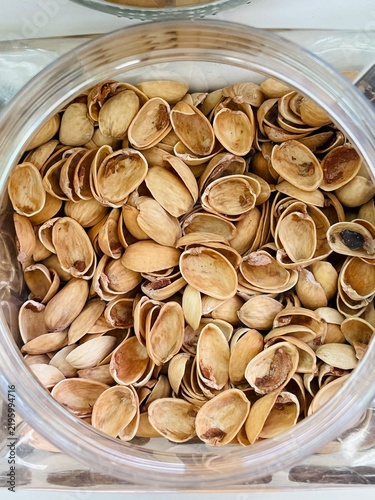 Quadro su tela close overhead view of many empty pistachio shells filling clear jar, showing be