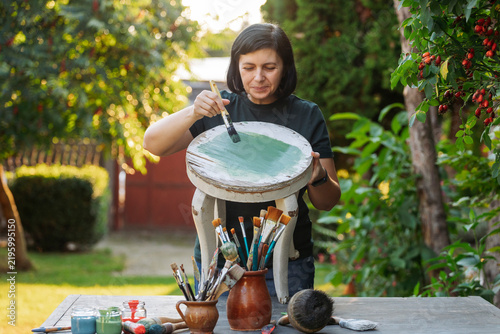 Mid woman painting furniture outdoors at home, relocation and diy concept.