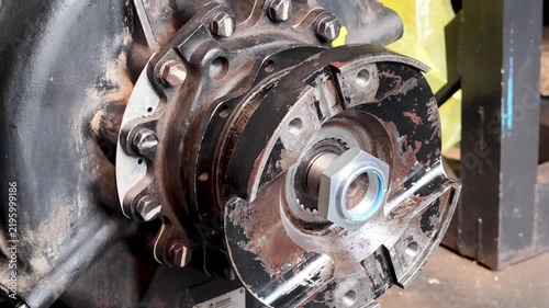 Heavy machinery output flange assembly secured with large lock nut in mechanical workshop.