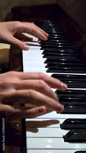 Close-up of female fingers playing on black and white piano keys in a music studio background