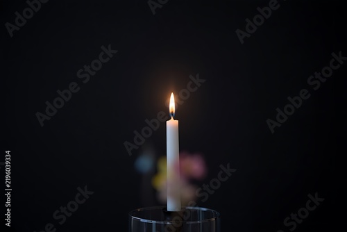 Single candle burning in darkness