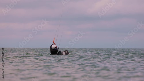 Action shot of a lone kitesurfer on Wingfoil with kite gliding across rough ocean waters on an overcast day. Extreme water sports and active lifestyle concept. Flying over water in slow motion..