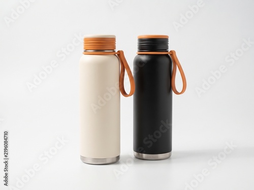 Two minimalist stainless steel thermos water bottles in cream and black color with orange silicone carrying strap isolated on seamless white studio background. Modern reusable drinkware mockup.