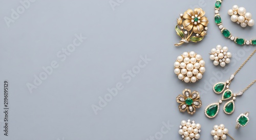 Textured Gray Background with Bottom-Right Corner Arrangement of Pearl and Emerald Jewelry