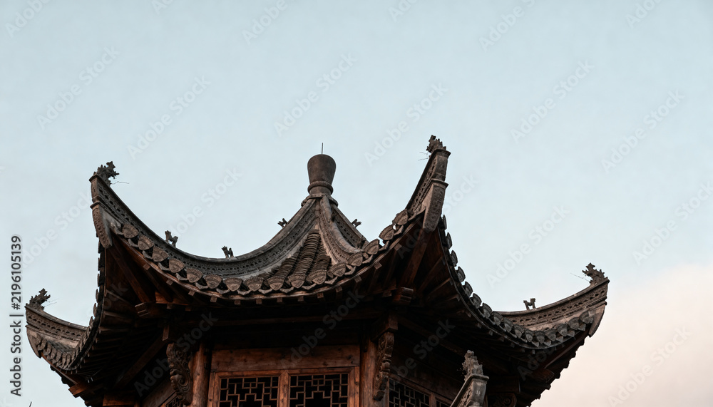 Fototapeta premium Traditional Asian pagoda roof with intricate wooden carvings and sweeping curved eaves, set against a soft overcast sky, emphasizing cultural heritage
